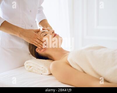 Beautiful woman enjoying facial massage with closed eyes Stock Photo
