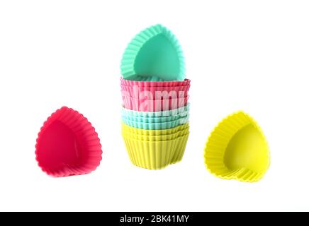 Multi-colored silicone cake baking dishes isolated on a white background. Silicone baking dishes in the shape of a heart. Copy space. Stock Photo