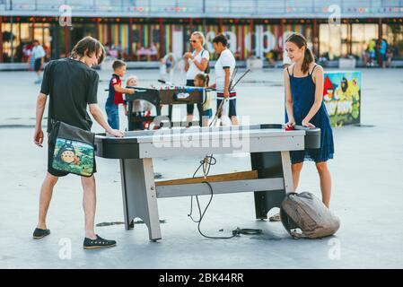 Moscow, Russia - AUGUST 9, 2014: teens play air hockey on a table in a Sokolniki park amid other playing people Stock Photo