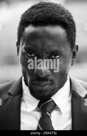 Face of stressed African businessman looking angry in black and white Stock Photo