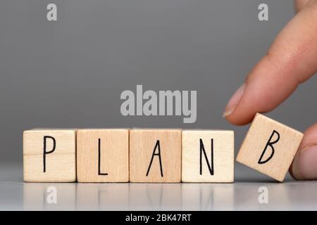 Wooden cubes with the word Plan B on grey background and human finger, business concept background Stock Photo