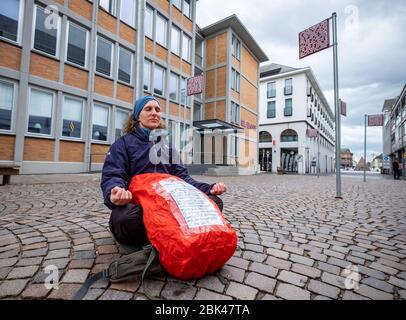 Deutschland. 01st May, 2020. In Karlsruhe, at the Platz für Grundrechte, there are street signs with statements on the subject of law (artwork by Jochen Gerz). A woman is sitting on one of the signs with the poster of fundamental rights and meditating. GES/Daily life in (Karlsruhe) during the corona crisis, 01.05.2020 GES/Daily life during the corona crisis in Karlsruhe, Germany. 01.05.2020 | usage worldwide Credit: dpa/Ģ����ý Live News Stock Photo