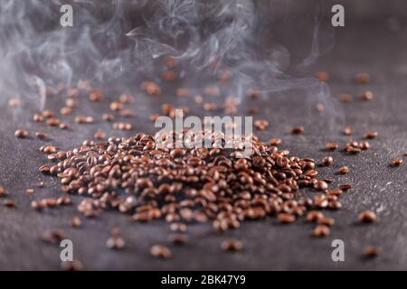 Freshly roasted aromatic coffee beans lie on a dark surface. Fresh morning fragrant drink concept Stock Photo