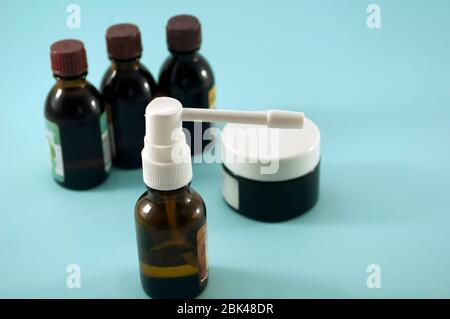 Glass bottle with dispenser with nozzle near three dark glass bottles on blue background Stock Photo