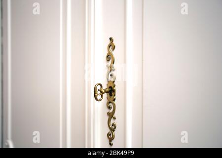 White cupboard doors with Golden key in keyhole, luxury antique design close-up wooden vintage doors Stock Photo