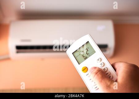 Split Air conditioner, Man operating remote controller Stock Photo