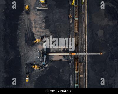 Loading coal anthracite mining in port on cargo tanker ship with crane bucket of train. Aerial top view