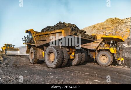 Big yellow mining truck laden anthracite moves open pit coal mine Stock Photo