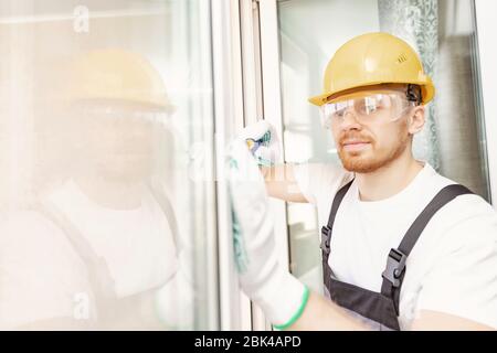 Worker man installs plastic windows and doors with double-glazed white Stock Photo