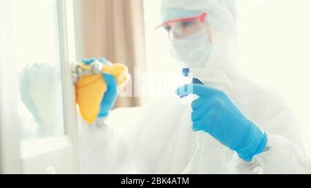 Disinfection and cleaning door handles of house from infection with virus and microbes in biochemical suit. Coronavirus protection concept Stock Photo