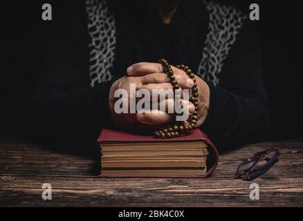 Old Woman with closed hands holding rosary on holy book staying at home and praying for protection ageainst coronavirus covid-19 pandemi concept. Stock Photo