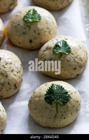 Buns made from yeast dough with nettles, decorated with nettle leaves on an iron pan. Stock Photo