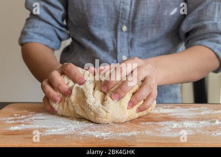 Baker hands making dough on wooden board in kitchen. Woman kneads dough Stock Photo