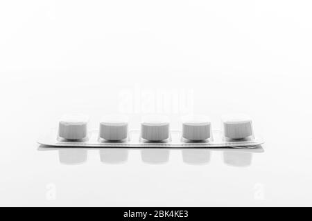 Pills in white foil capsule tablet packaging lay flat and isolated on white background Stock Photo