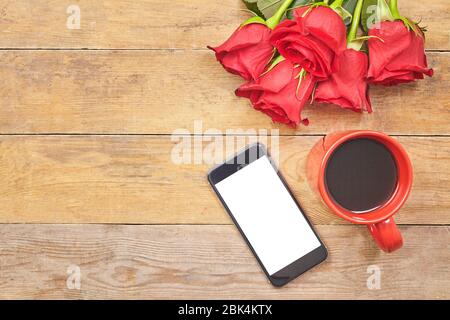 Top view Hot coffee latte with a red rose and smartphone on a wood table. Stock Photo