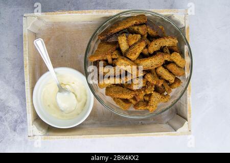Rye breadcrumbs in a glass plate together with garlic sauce on a gray marble table. Top views with clear space Stock Photo