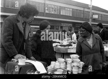 Customers look at a stall outdoors on Longsight Market, Dickenson Road, Manchester, England, uk, in 1974. Stock Photo