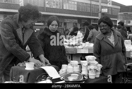 Customers look at a stall outdoors on Longsight Market, Dickenson Road, Manchester, England, uk, in 1974. Stock Photo