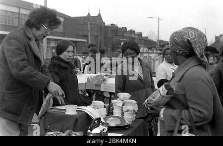 Customers look at a stall outdoors on Longsight Market, Dickenson Road, Manchester, England, uk, in 1974. Stock Photo