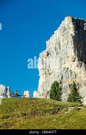 Man on a cell phone with Tofana di Rozes and the Dolomite Mountains towering overhead near Cortina d'Ampezzo, Veneto, Italy Stock Photo