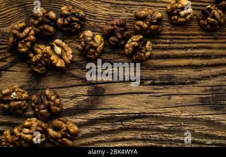 Walnut scattered on the wooden vintage table. Copy space. Walnuts is a healthy vegetarian protein nutritious food. Almonds on rustic old wood. Stock Photo
