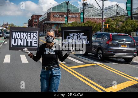 Brooklyn, United States Of America . 01st May, 2020. A car caravan protestor shows solidarity with essential workers, who are put at risk every day with low pay and without necessary protective gear outside a Whole Foods store in Brooklyn, New York, on May 1, 2020. Whole Foods and Amazon owner Jeff Bezos has made a profit of over $24 billion during the COVID-19 pandemic while Amazon and Whole Foods employees have complained about dangerous working conditions. (Photo by Gabriele Holtermann-Gorden/Sipa USA) Credit: Sipa USA/Alamy Live News Stock Photo
