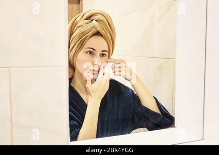 young millennial performs cosmetic procedures in front of a mirror Stock Photo