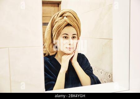 young millennial performs cosmetic procedures in front of a mirror Stock Photo