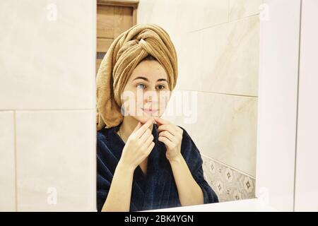 young millennial performs cosmetic procedures in front of a mirror Stock Photo