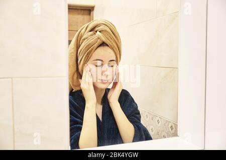 young millennial performs cosmetic procedures in front of a mirror Stock Photo