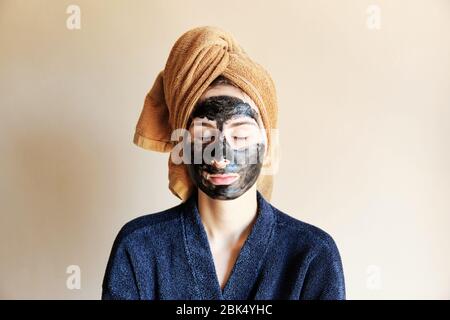 millennial put a black mask on her face and tied a towel on head Stock Photo