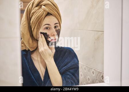 young millennial performs cosmetic procedures in front of a mirror Stock Photo