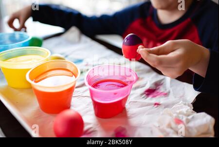 Close up of boy dipping an egg into dye to color it for easter. Stock Photo