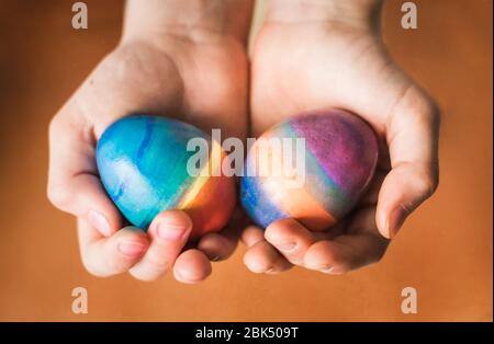 Close up of hands holding two brightly colored easter eggs. Stock Photo