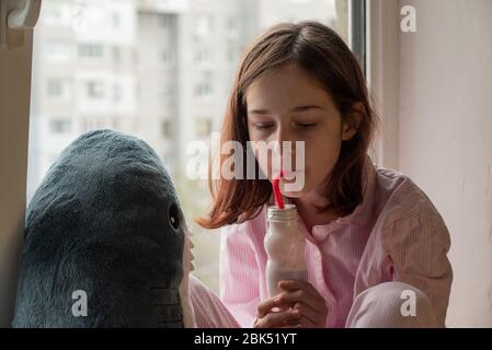 The little girl is drinking yogurt. Girl drinks yogurt. Cute little girl drinking yogurt at home. Food photography. Healthy drink. Diet and healthy ea Stock Photo