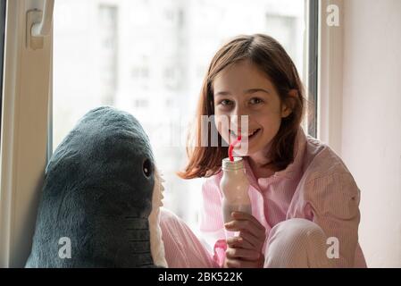 The little girl is drinking yogurt. Girl drinks yogurt. Cute little girl drinking yogurt at home. Food photography. Healthy drink. Diet and healthy ea Stock Photo