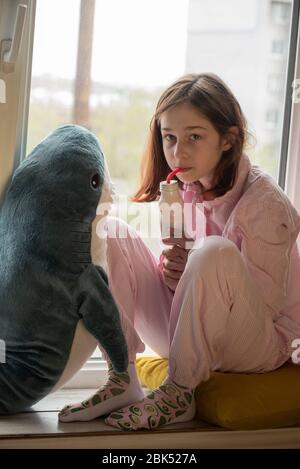 The little girl is drinking yogurt. Girl drinks yogurt. Cute little girl drinking yogurt at home. Food photography. Healthy drink. Diet and healthy ea Stock Photo