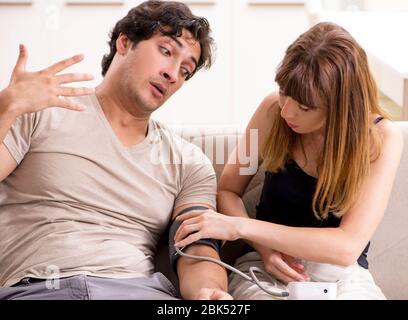 The wife checking husband's blood pressure Stock Photo