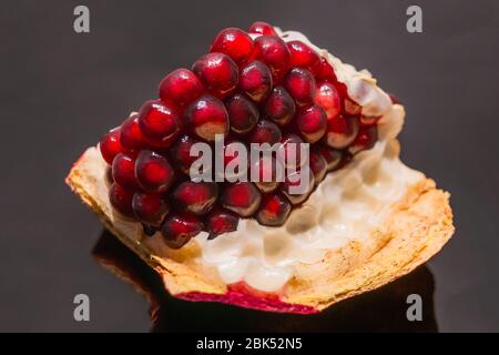 Big Ripe Red Granets or Garnets close up on glossy black backgground. Stock Photo