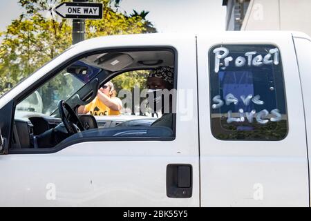 Man driving vehicle wearing face mask with sign drawn on window during the Coronavirus outbreak Stock Photo