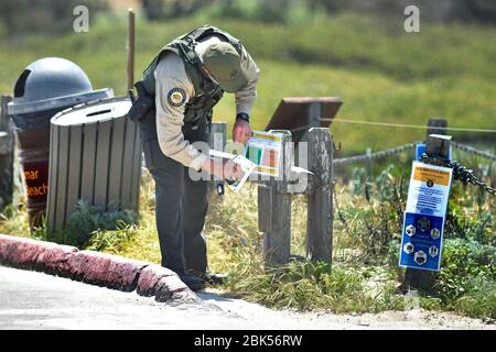 Pacific Grove, California, USA. 1st May, 2020. California State Parks Peace Officer posting signs to clarify the.Recreation Rules for Asilomar State Beach during the COVID-19 Shelter in Place Order Credit: Rory Merry/ZUMA Wire/Alamy Live News Stock Photo
