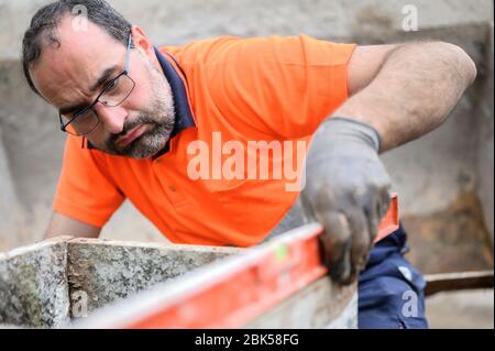 Construction worker checking the bubble level while working at construction site. Building construction . Stock Photo