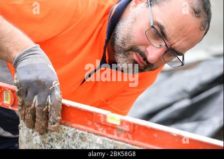 Construction worker checking the bubble level while working at construction site. Building construction . Stock Photo