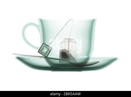 Teacup saucer teaspoon and teabag, coloured X-ray. Stock Photo