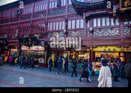 Tourists pass a Starbucks Coffee shop in a traditional looking