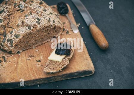 Homemade soda spelt bread with butter and dark cherry jam on a wooden board Stock Photo