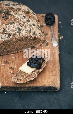 Homemade soda spelt bread with butter and dark cherry jam on a wooden board Stock Photo