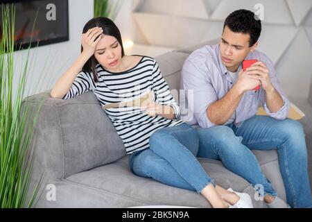 Anxious woman with letter, a husband next with smartphone. Stock Photo