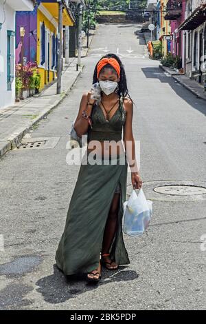 Young woman carrying grocery bags in empty city during Coronavirus lockdown in Colombia Stock Photo