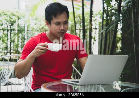 man using laptop enjoying the taste and the aroma of a coffee Stock Photo